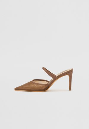 Mules à talons marron avec un bout pointu, des détails en mesh et une fine bride autour de la cheville. Le talon est fin et mesure environ 10 cm.