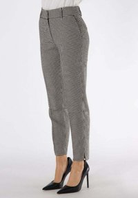 Pantaloni a quadri houndstooth in bianco e nero con design affusolato, dotati di tasche anteriori e una piccola fessura all'orlo.