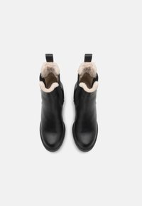 Botas negras de cuero hasta el tobillo con un suave forro de piel de color beige, puntera redonda y lengüetas para facilitar su colocación. Superficie lisa con detalles de costura.