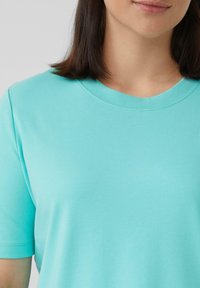 Turquoise korte mouwen t-shirt in zachte stof, met een ronde hals en een gladde textuur, met subtiele stiksels langs de kraag.