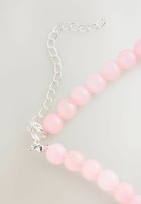 Pink bead necklace made of smooth, round rose quartz beads, featuring a silver metal clasp and adjustable chain.