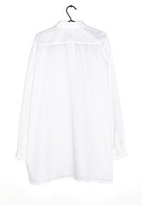 Bílá košile s dlouhým rukávem vyrobená z bavlny. Má klasický límec, manžety na knoflíky a rovný střih s hladkou texturou.