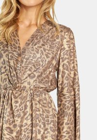 Leopardenmuster Kleid aus gold- und braunmetallic Stoff, mit Wickeldesign, langen Ärmeln und tailliertem Bund.
