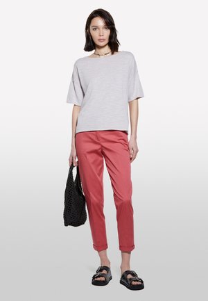Haut à manches courtes gris clair, pantalon corail, sandales noires et sac tissé noir. Tissu lisse et coupe décontractée avec des poignets retroussés.