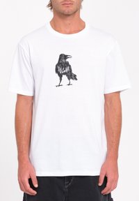 T-shirt en coton blanc avec un croquis noir d'un corbeau sur le devant. Manches courtes, col ras du cou, coupe normale. Aucun motif ou accent supplémentaire.