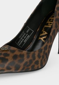 Καφέ γόβα με λεοπάρ σχέδιο, μυτερή μύτη, μαύρο εσωτερικό, χρυσό λογότυπο "REPLAY" και ετικέτα μεγέθους EUR 37, κατασκευασμένη στην Κίνα.