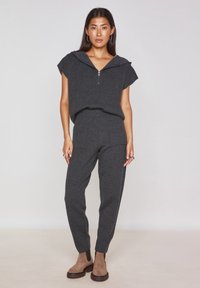 Pullover grigio a maglia con colletto con zip e maniche corte, abbinato a pantaloni tapered coordinati. Presenta due tasche frontali e caviglie con orlo.