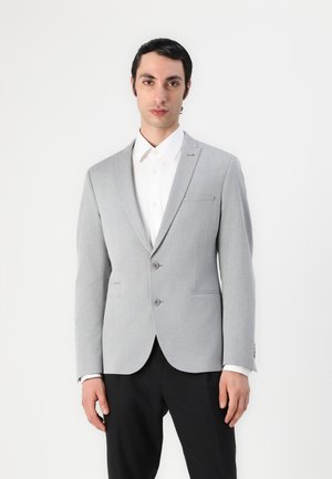 Light gray suit jacket with a notched lapel, two buttons, and two front pockets. Worn over a white shirt with a smooth texture.