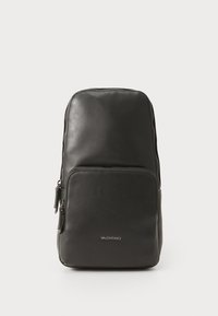 Zaino in pelle nera con una texture liscia, dotato di un tascone principale con zip e di una tasca frontale. Logo visibile sul davanti.