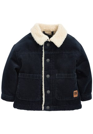 Veste en velours côtelé noir avec col en sherpa crème, boutons-pression sur le devant, deux grandes poches avant, et un petit écusson logo marron sur la poche.