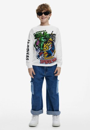 Chemise blanche à manches longues avec impression de bande dessinée colorée mettant en scène Hulk et Spider-Man. Pantalons en denim bleu avec poches latérales et ourlets retroussés.