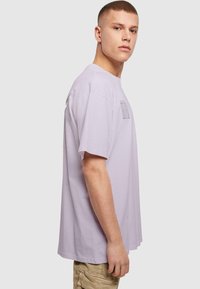 Lys lilla bomulds T-shirt med rund hals og korte ærmer, der har et geometrisk grafisk print foran.