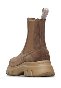 Bottines en daim marron avec des panneaux élastiques sur les côtés, une épaisse semelle en caoutchouc beige et une languette à l'arrière. Présente une texture douce et une forme arrondie.