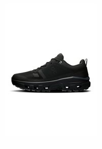 Baskets de sport noires avec une tige en mesh, des accents synthétiques et une semelle texturée avec des crampons proéminents pour une meilleure adhérence. Comprend un détail réfléchissant.