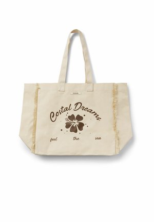 Sac cabas en toile beige avec de longues anses, des détails à franges sur les côtés, et le texte « Costal Dreams feel the sea » avec un graphisme de fleur d'hibiscus.