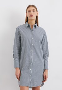 Knoopshirt-jurk in marineblauw en witte verticale strepen, met een kraag, lange mouwen en een rechte snit met een iets langere achterkant.