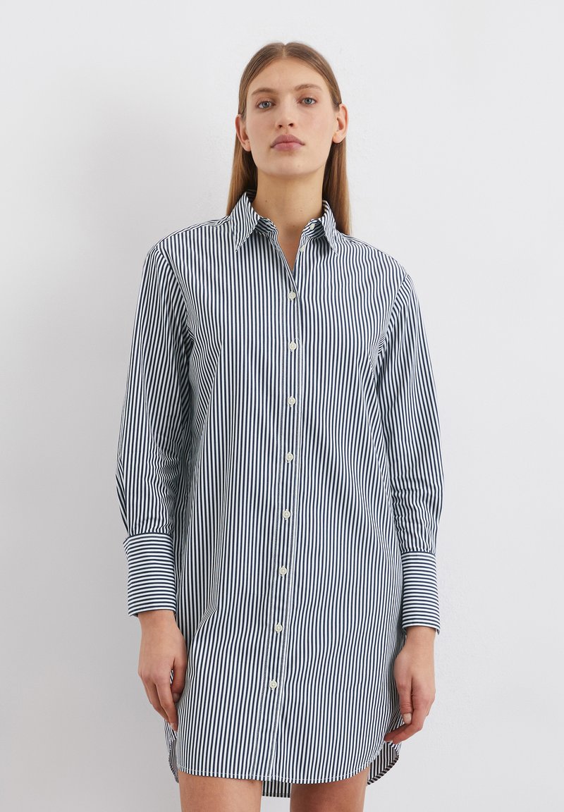 Knoopshirt-jurk in marineblauw en witte verticale strepen, met een kraag, lange mouwen en een rechte snit met een iets langere achterkant.