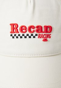 Bežna kapa s izvezenim "Recap RACING" u crvenoj boji, s kockastim uzorkom u crnoj i bijeloj boji ispod. Mekana tekstura tkanine, zakrivljena vizir.