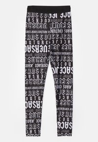 Juodos leggingai su baltu pakartotiniu grafiniu raštu, kuriame pavaizduota įvairi stilizuota tekstas, įskaitant "Versace Jeans Couture", ir vientisas juosmuo.