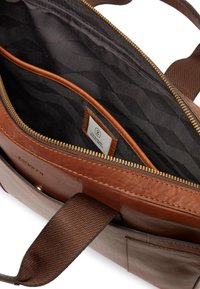 Brun läderväska med en texturerad yta, med ett guldzipper och mörk mönstrad foder. Synliga inre fickor och remmar.