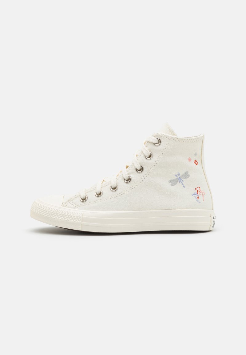 Zapatillas altas de lona color crema con suela de goma blanca. Presentan coloridos diseños bordados de insectos y flores en los laterales.