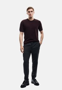 Mørk maroon kortærmet sweater kombineret med grå trækbåndbukser og sorte lædersko. Ensfarvede, enkel design, letvægtsstof.