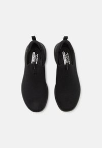 Black slip-on shoes with a textured mesh upper, elastic top, and cushioned insole. Rounded toe and flexible rubber outsole.