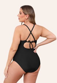 Zwart éénstuk badpak met een kruislingse achterkant en een gestrikt detail onder een open uitsnede. Soepele textuur en aansluitend ontwerp.