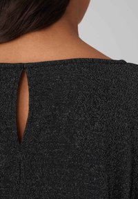 Schwarzes, strukturiertes Stoffoberteil mit dezenten metallischen Fäden, ausgestattet mit einem Schlitz im Rücken und einem weiten Ausschnitt. Einfaches Design, elegante Ausführung.