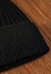 Must mustre look, mille ribikonstruktsiooniga ja volditud äärega. Taustal puidust pind kontrasti lisamiseks.