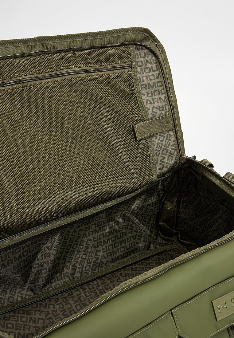 Olivgrüne Reisetasche aus strukturiertem Material, mit einem Netzfach und markiertem Futter, hat einen Reißverschluss und ein geräumiges Innenfach.