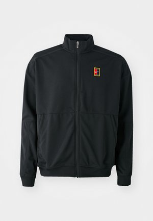 Black zip-up jacket with high collar, ribbed cuffs and hem, and a small red, yellow, and black Nike logo on the left chest.