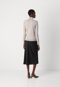 Lys grå tætsiddende sweater med lange ærmer og ribbet kant, parret med en svævende sort satin-nederdel og sorte slingback-hæle.
