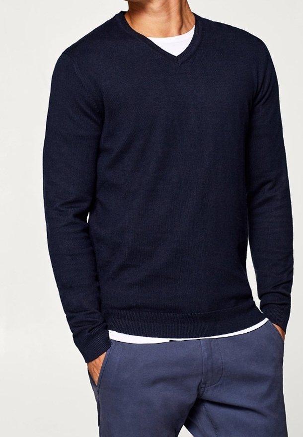 Navy blue v-neck sweater, knit texture, long sleeves, ribbed cuffs and hem, worn over a white t-shirt, paired with light blue trousers.