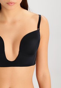 Black plunge bra with smooth fabric, wide straps, and a low-cut design. Features a hook-and-eye closure and seamless cups.