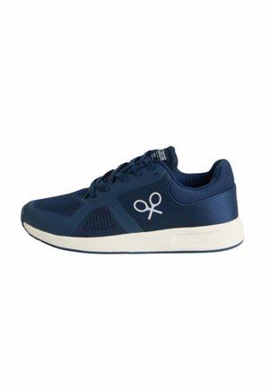 Zapatilla azul marino con cordones, suela blanca y logo de tijeras blancas en el lateral, diseñada para uso casual o deportivo.