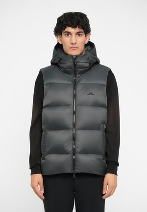 Puffer vest v tmavošedej farbe s hladkým, lesklým povrchom. Obsahuje odnímateľnú kapucňu, predný zips a decentné logo značky na hrudi.