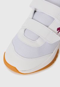 Baskets blanches avec semelle orange, tige en mesh et deux sangles Velcro, arborant un petit motif bordeaux sur le côté.