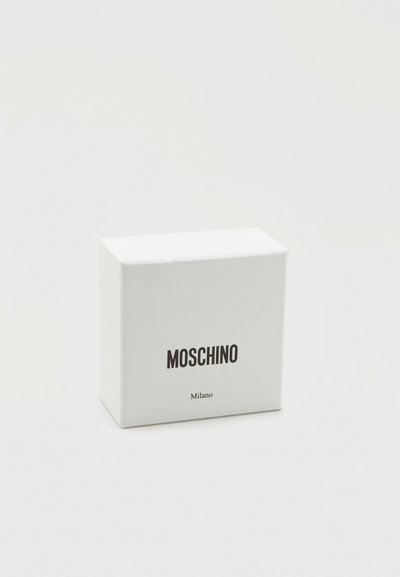 Λευκό υφασμάτινο κουτί με καπάκι, με εκτυπωμένα τα λόγια «MOSCHINO» και «Milano» με έντονη μαύρη γραμματοσειρά μπροστά. Απλός και ορθογώνιος σχεδιασμός.
