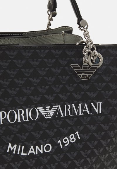 Borsa tote in pelle nera con motivo a logo aquila in rilievo. Presenta hardware argentato, un charm e testo bianco in rilievo, arricchendo il design.