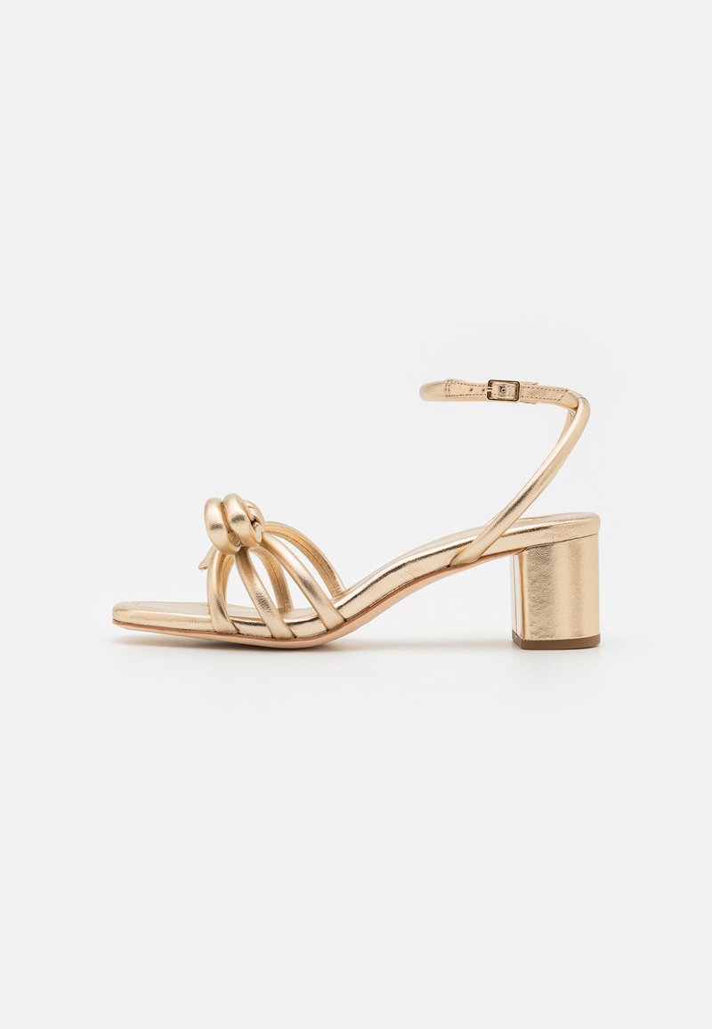 Gold metallic heeled sandal with open toe, featuring a braided front design and ankle strap with a buckle. Block heel for stability.