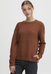 Pull en tricot brun texturé avec un col rond, des manches longues et un ourlet côtelé. Présente une coupe décontractée et un motif subtil.