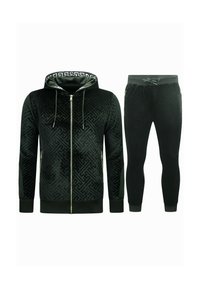 Zwart fluwelen trainingspak met een rits-hybride hoodie met een geometrisch patroon en gouden hardware, gecombineerd met tapse broekspijpen met elastische boorden.