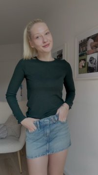 Top de manga longa riscado verde combinado com uma saia mini de denim azul claro. A saia possui botão na frente e passantes para cinto, com uma textura suave.