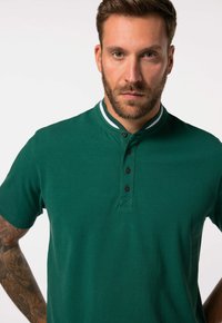 Zelená polo košile s krátkým rukávem, zapínáním na knoflíky a kontrastním proužkovaným límcem, vyrobená z hladké, texturované látky.