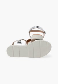 Sandali open-toe con suola bianca testurizzata, cinturini metallici argento e accentuazione in pelle marrone; dotati di chiusura con fibbia e design minimalista.