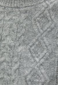 Grauer Strickpullover mit einem Zopfstrickmuster, das rautenförmige und unterschiedliche Texturen aufweist. Rundhalsausschnitt und weicher, dicker Stoff.