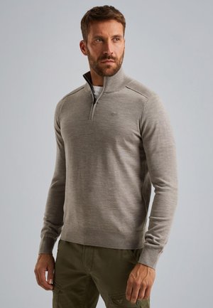 Pull en gris clair avec un zip quart, des poignets côtelés et une texture subtile. Présente des coutures latérales aux épaules et un petit emblème sur la poitrine.