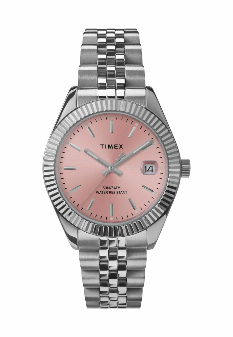 Montre-bracelet Timex avec un cadran rose, des marqueurs argentés et un bracelet en acier inoxydable. Dispose d'une lunette cannelée et d'un affichage de la date à 3 heures. Résistante à l'eau jusqu'à 50m.