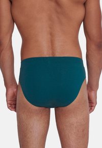 Herrenboxershorts aus dunkelblauem Stoff, mit einem niedrigen Schnitt und glatter Textur. Einfaches Design ohne sichtbare Muster oder Akzente.